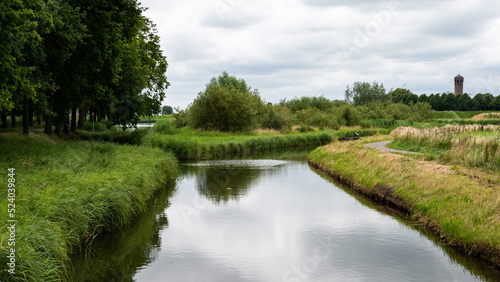 Green surroundings of the village Heusden reflecting in the canal