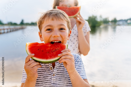 Two happy children enjoy watermellon having picnic at summer sunny day at nature. photo