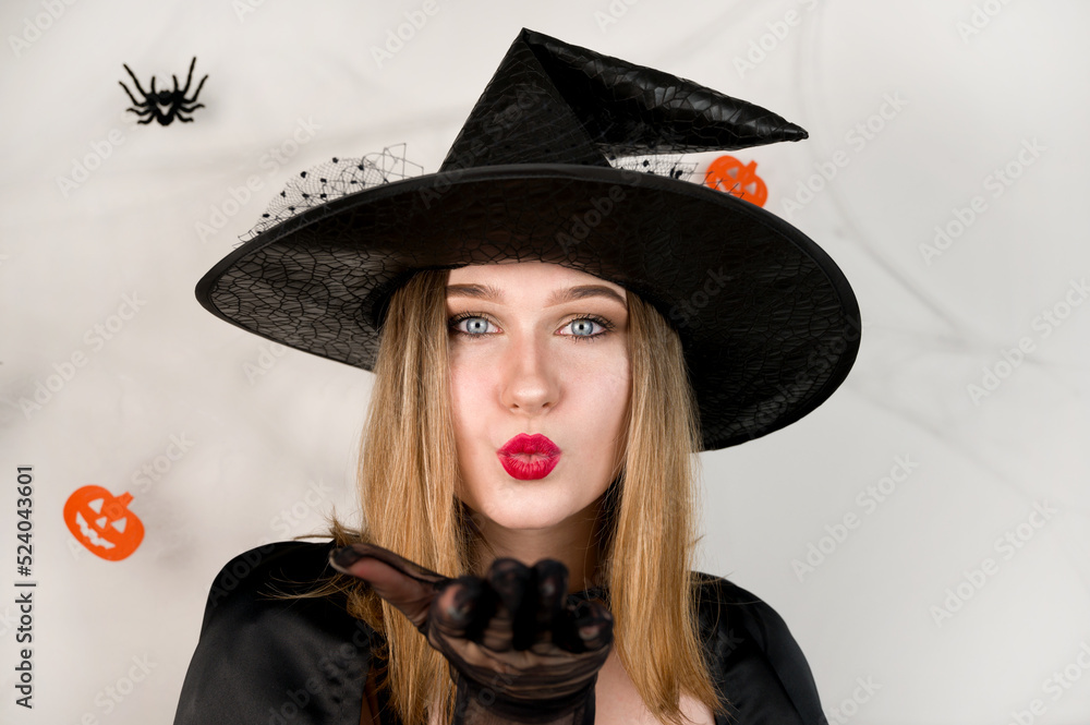 Closeup portrait of cute witch sending kiss against halloween background.Holidays sale.October 31 party