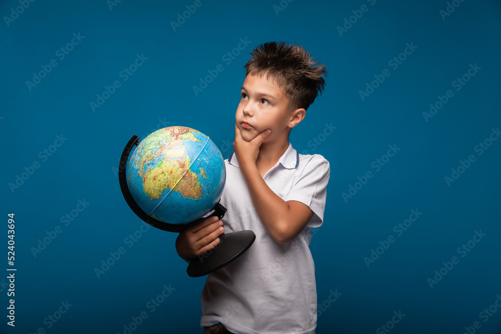 a boy with a globe in his hands.the student looks at the globe and thinks. studying geography a boy with a globe in his hands.the student looks at the globe and thinks. studying geography