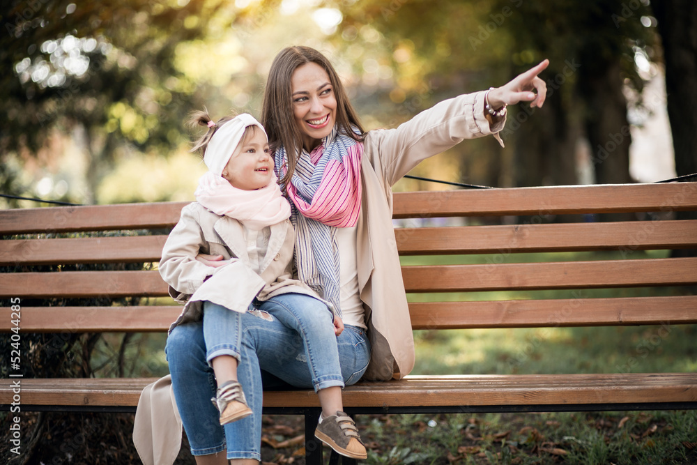 Mother with little daughter sitting on the bench in park Mother with little daughter sitting on the bench in park