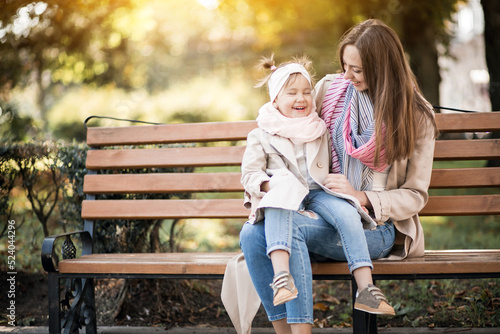 Mother with little daughter sitting on the bench in park