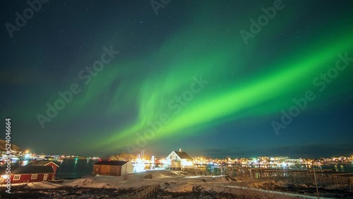 Beautiful aurora borealis, Northern lights over illuminated fishing village on arctic ocean coastline at Lofoten Islands, Norway
