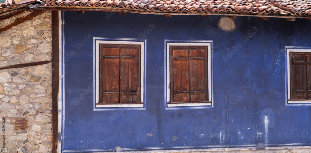 Old wooden windows with closed shutters on blue wall of vintage house