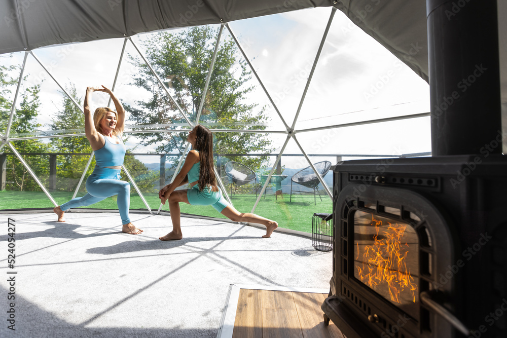 mother and daughter yoga in glamping dome tent domestic Stock