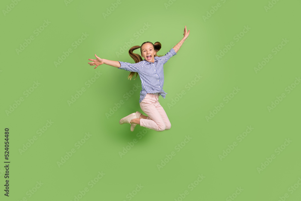 Photo of positive cheerful kid girl jump high raise hands aside wear striped clothes isolated bright color background