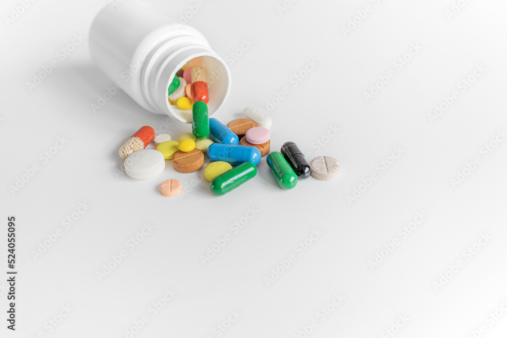 Bottle with multi-colored pills on a white background.