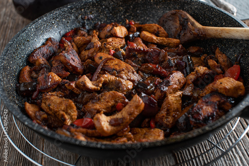 Honey glazed chicken stir fry with red onions, garlic and bell peppers in a pan