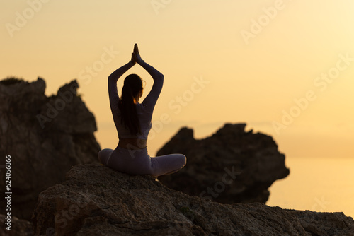 Serenity and yoga practicing at sunset, meditation. silhouette on sea background with sunrise