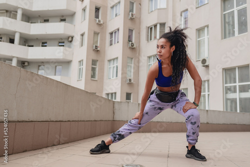 attractive black african american woman in sport fitness outfit on rooftop making work out