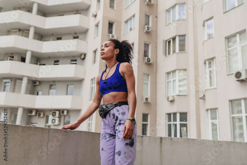 attractive black african american woman in sport fitness outfit on rooftop making work out