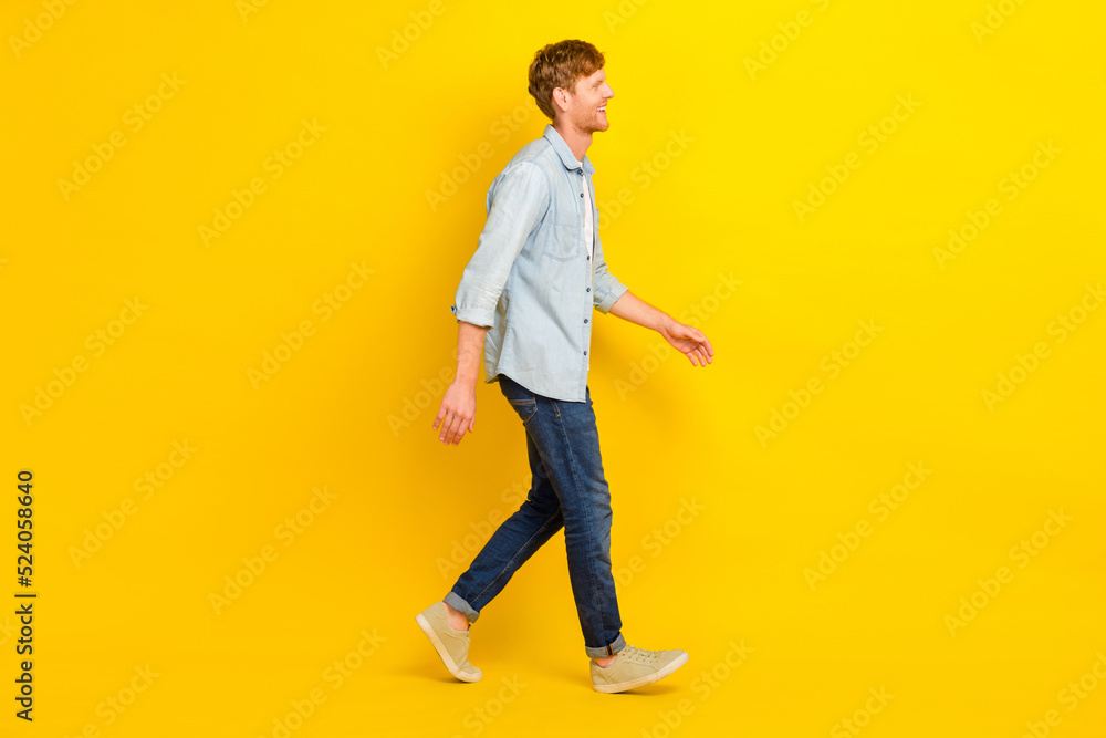Photo of pretty positive man wear jeans shirt walking looking empty space isolated yellow color background Photo of pretty positive man wear jeans shirt walking looking empty space isolated yellow color background