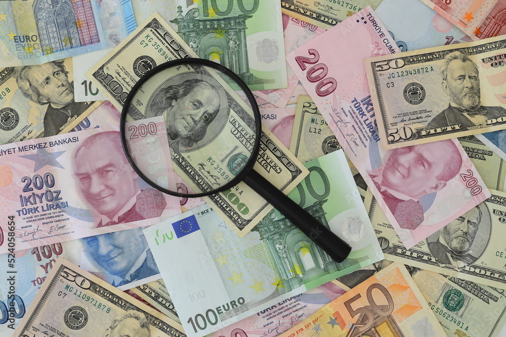Fototapeta premium Banknotes spread out on a table with a calculator and a magnifying glass.