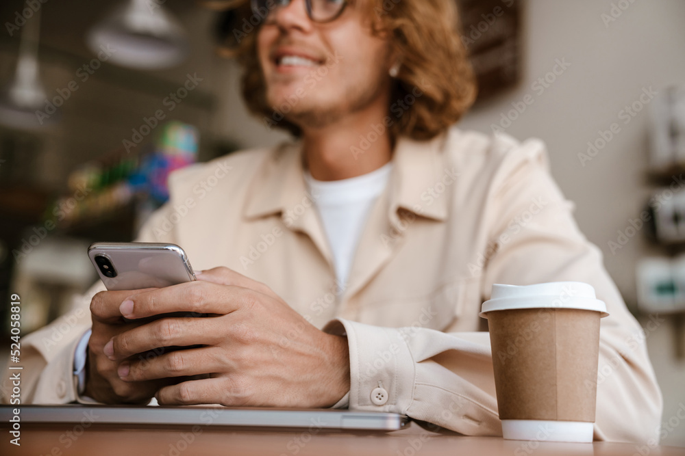 Cropped portrait of young long-haired man in glasses holding phone Cropped portrait of young long-haired man in glasses holding phone