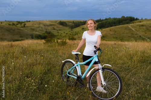 Young redhead woman with a bicycle in the field