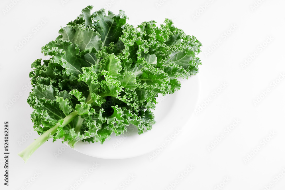 Green kale cabbage leaves on white background. Textured leaves in white plate. Top view and copyspace. Healthy food concept. Green kale cabbage leaves on white background. Textured leaves in white plate. Top view and copyspace. Healthy food concept.