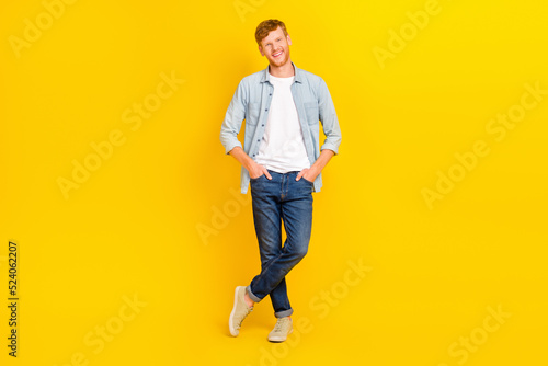 Photo of cool cheerful guy dressed denim shirt walking smiling isolated yellow color background