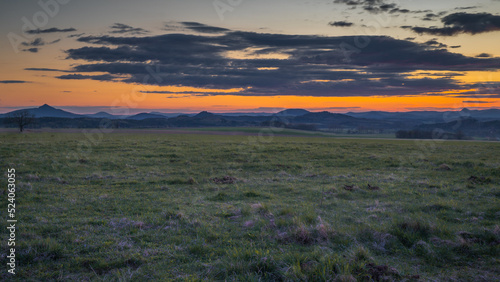 Romantic sunset on a field in northern Bohemia. Sky is calm and  with few clouds and sun above the horizon.