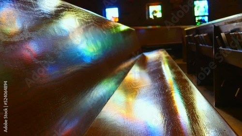 Wooden pew with rainbow lights reflecting from stained window in a church photo