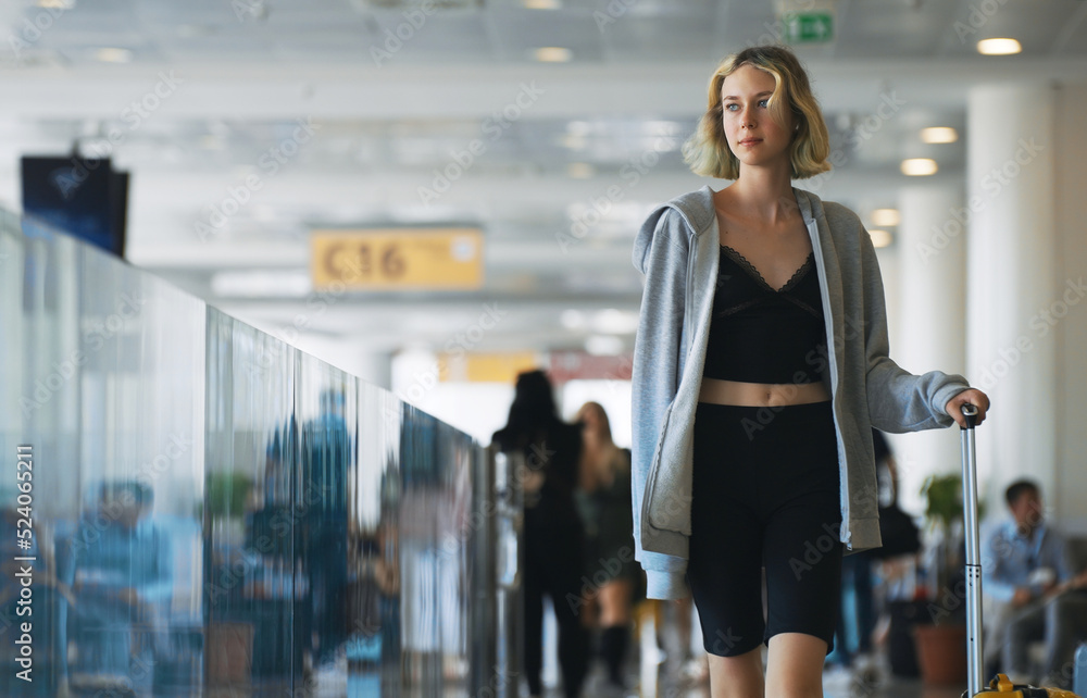 Tween girl with suitcase walking in airport terminal.