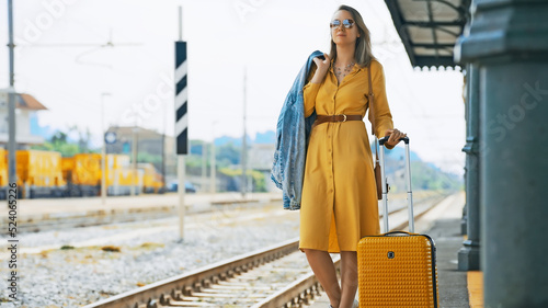 Woman with travel suitcase is waiting for a train. © M-Production