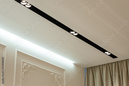 Suspended ceiling with halogen spots lamps and drywall construction in empty room in apartment or house. Stretch ceiling white and complex shape.