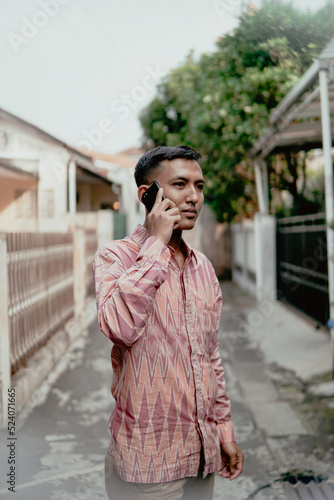 Man wear traditional Indonesian cltohes (batik) and are on the phone © Terang Bulan Gallery