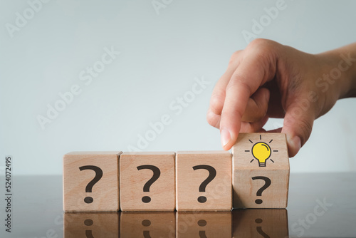 Creativity and inspiration ideas,Business idea,Thinking, invention concept.,Hand Changing or flipping Question Mark icon to Glowing Light bulb icon on wooden cube over white wall background.