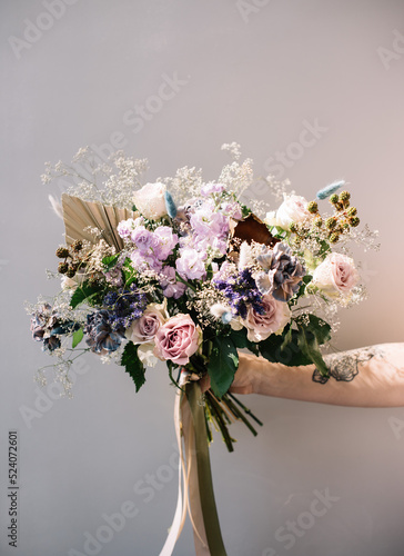 Very nice young woman holding big and beautiful bouquet of fresh roses, matthiola and other flowers in purple colors, cropped photo, bouquet close up