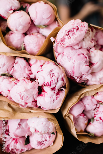 Freshly delivered to flower shop pink peonies packed in craft paper 