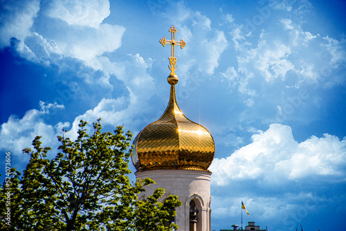 Large golden domes of the church against the background of clouds and blue sky in summer
