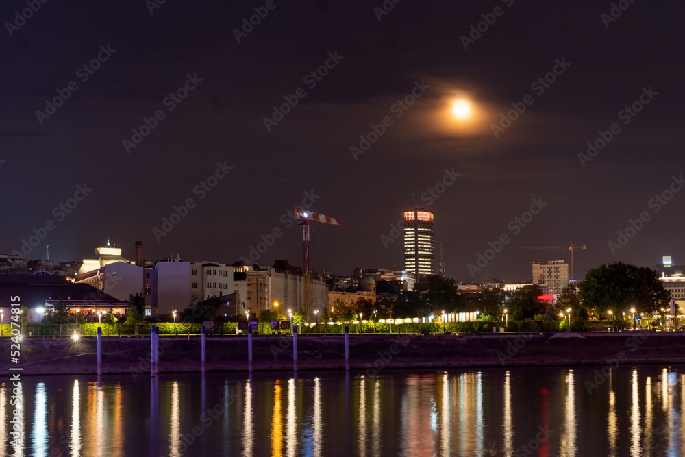 Belgrade and river Sava at night. Beautiful city view with moon over the city