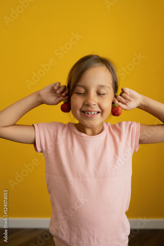 Girl making earrings from strawberries photo