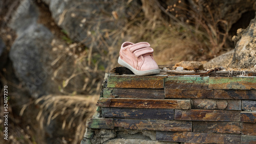 Pink lost baby boot lost during escape, Lost on the street children's shoes. a woman's hand takes a small sneaker in her hand.