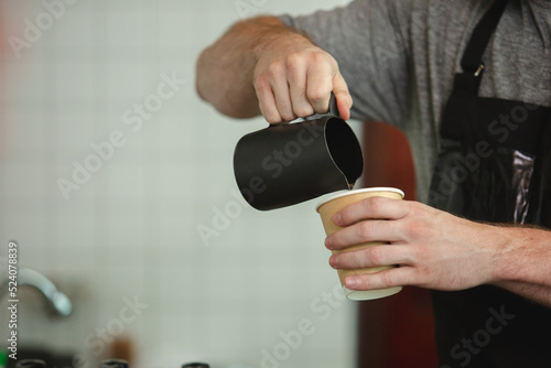 Closeup image hands man pouring coffee in paper cup.