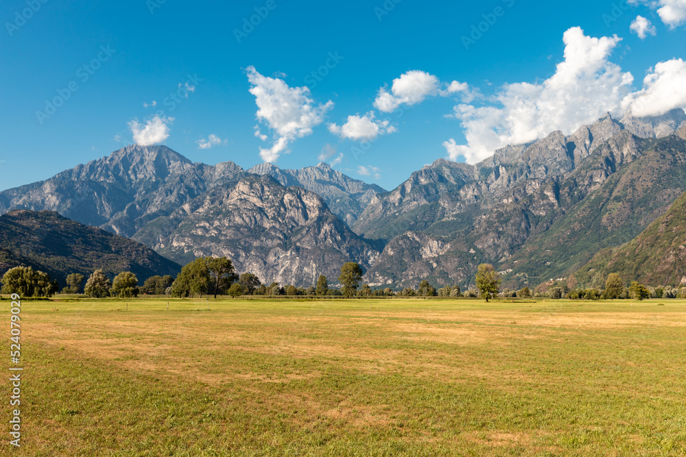 Panoramic view of a meadow with alpine mountains in the background. Spluga Pass
