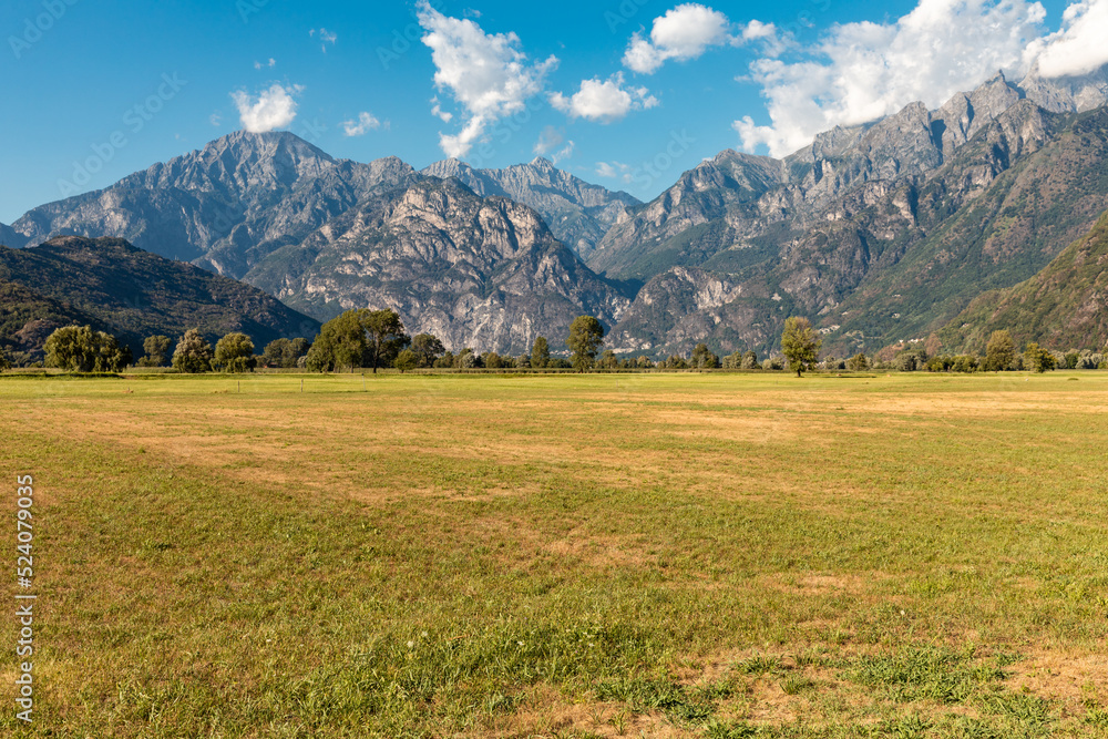 Panoramic view of a meadow with alpine mountains in the background. Spluga Pass
