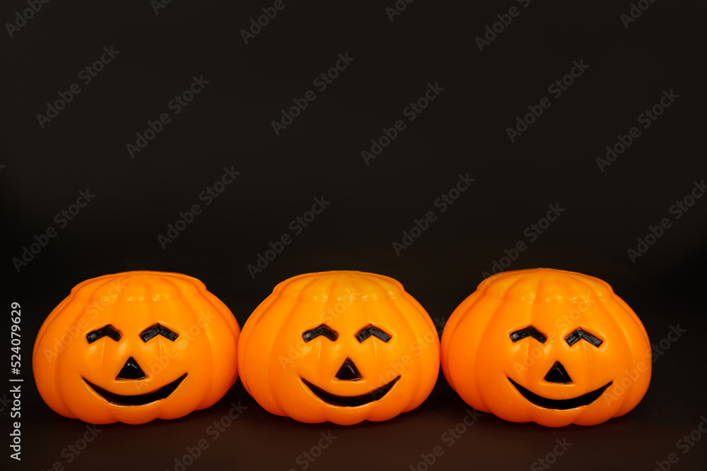 Pumpkins are orange, plastic with smiling faces on a black background. Postcard with copy space. The concept of congratulation, invitation, holiday, party, promotion, announcement. High quality photo Pumpkins are orange, plastic with smiling faces on a black background. Postcard with copy space. The concept of congratulation, invitation, holiday, party, promotion, announcement. High quality photo
