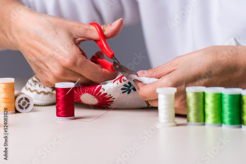 woman's hands arranging clothes, thread and needle, dressmaker, workshop, needlework, sewing clothes, fabric embroidery, selective focus