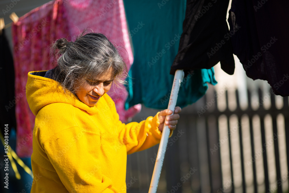 Obraz premium Woman Using Clothe Lines To Dry Clothes In an Energy Efficient Way