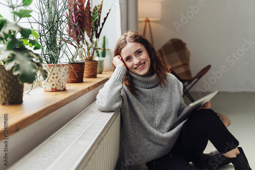 Young woman leaning against radiator with computer tablet in hand