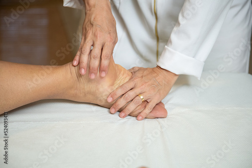Close up em mãos de massagista aplicando massagem terapêutica no pé de um paciente.