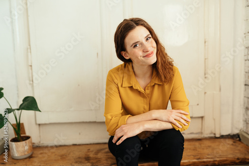 Young woman sitting on wooden stairs and looking cheekily at camera photo