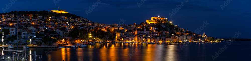 Evening city of Sibenik in Croatia, reflection of the lights of the night city, panoramic shot