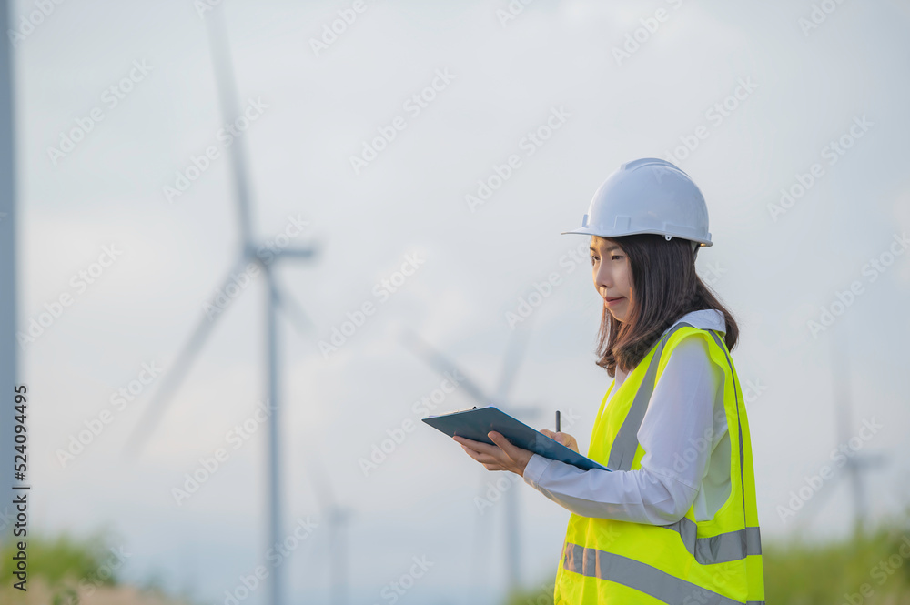women engineer working and holding the report at wind turbine farm Power Generator Station on mountain,Thailand people women engineer working and holding the report at wind turbine farm Power Generator Station on mountain,Thailand people