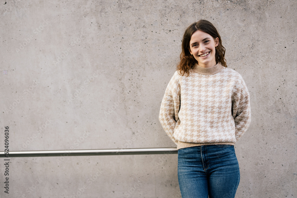 Young woman leaning against concrete wall and looking at camera Young woman leaning against concrete wall and looking at camera