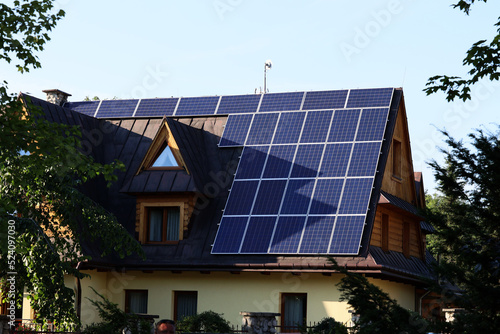 Panele solarne na skośnym dachu budynku mieszkalnego. photo