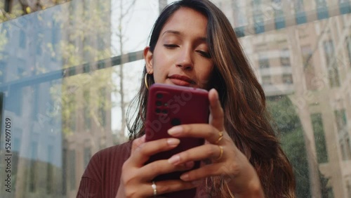 Young businesswoman standing on street and text messaging in city