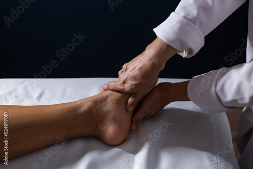 Quadro su tela Detalhe das mãos de massagista aplicando massagem terapêutica no pé de um paciente que está deitado em uma maca com lençol branco
