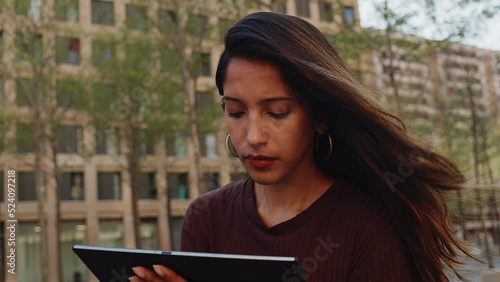 Young businesswoman standing on street working with tablet and mobile phone